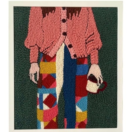 Tableau brodé représentant une silhouette féminine en pantalon patchwork et gilet rose, réalisé à la main en punch needle.