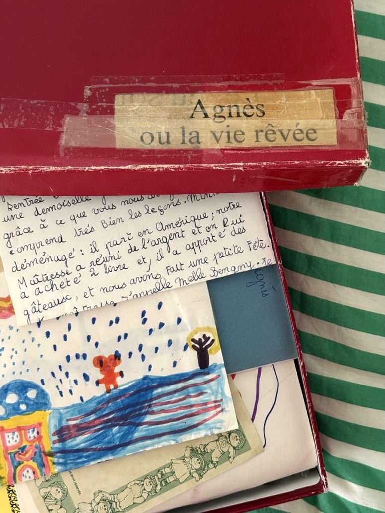 Boîte rouge portant l'inscription « Agnès ou la vie rêvée », ouverte sur des lettres manuscrites, des dessins d'enfance et des souvenirs personnels.